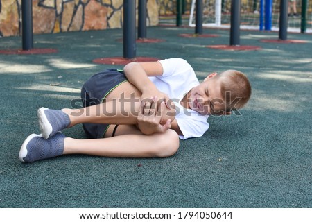 boy fell and hurt himself on the outdoor playground. knee injury child sports injury. boy crying in pain Royalty-Free Stock Photo #1794050644