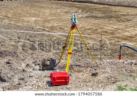 Total station standing on a tripod at construction site. Surveyor engineering with tacheometer or theodolite. Royalty-Free Stock Photo #1794057586
