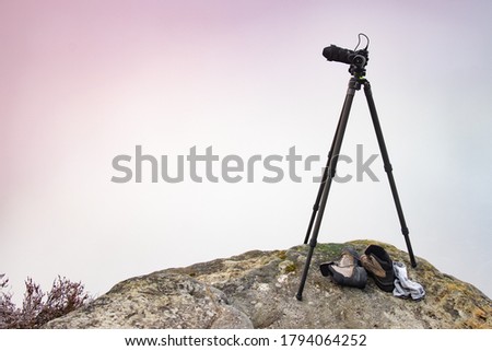 Modern professional camera on a tripod, outdoor photography in wildlife. Mountains background.Camera on a tridop takes a picture of a mountain landscape