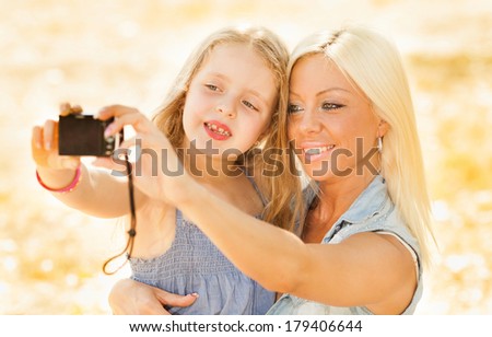 Beautiful, happy mother and daughter pose for a self portrait in the nature