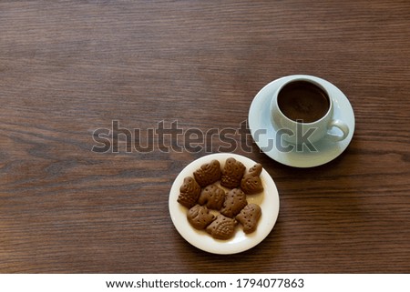Coffee cup with chocolate cookie on dark wooden background

