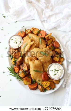Delicious homemade fish and potato chips with tarragon mayonnaise in a serving plate against white background copy space top view, flat lay. England traditional fried fish in batter served with chips