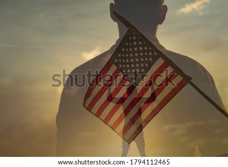 Silhouette of strong man standing next to USA flag. American hero concept.