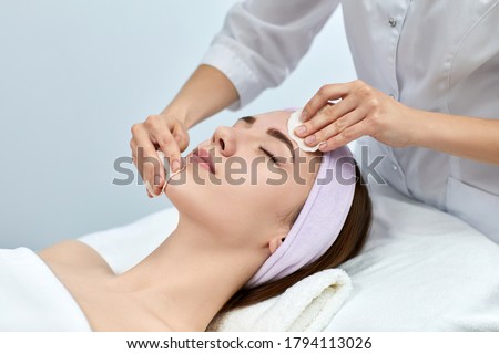 beautician cleanses skin of beautiful woman with a sponge. Perfect cleaning, spa treatment skincare face. Royalty-Free Stock Photo #1794113026