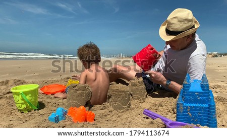 
Family at the beach building castle. Grandfather with child grandson at shore