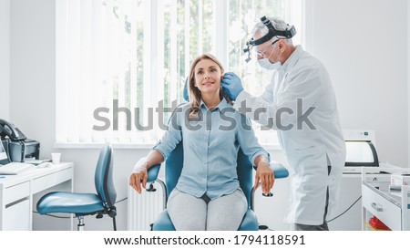 Doctor checking ear of middle aged woman using otoscope Royalty-Free Stock Photo #1794118591