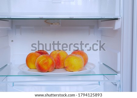 ripe peaches on white plate in refrigerator Royalty-Free Stock Photo #1794125893