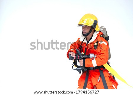 A portrait of Asian male firefighter in orange protective uniform, mask and helmet with fire extinguisher sitting on white background. 