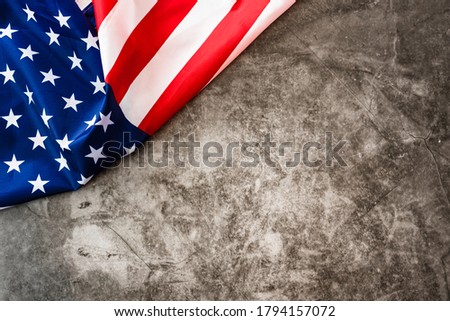 Striking colored American flag isolated in a corner on a stone gray background.