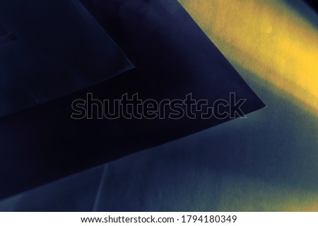 abstract background, composed of overlapping blue sheets of paper, creating geometric patterns, lit laterally by a beam of yellow light - POA, SAO PAULO, BRAZIL.