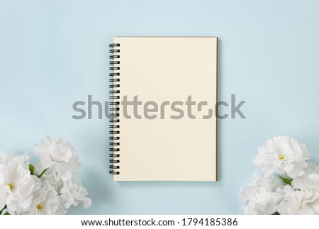 Spiral Notebook or Spring Notebook in Unlined Type and White Flowers at Bottom on Blue Pastel Minimalist Background