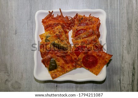 Warm keto cheese crisps or crackers with pepperoni and jalapenos as toppings served on a white plate.