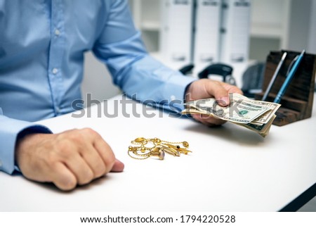 Man buying gold jewellry, pawn shop and us dollar banknotes Royalty-Free Stock Photo #1794220528
