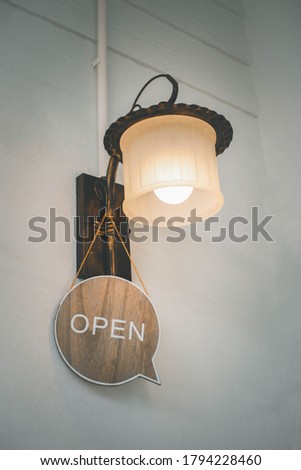 A business sign that says ‘Open’ on cafe or restaurant hang on the lamp at entrance. Vintage color tone style.