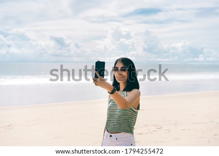 People relax in nature at the beach sea. Happy adult asian woman using smartphone take a  selfie photo for internet social message. Outdoor on day with sky background and copy space.