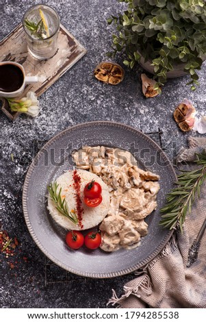 Rice with mushroom sauce and tomatoes. Coffee and water with lemon  on the wooden board 
