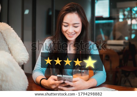 Young woman holding phone with five star services rating satisfaction. Royalty-Free Stock Photo #1794298882