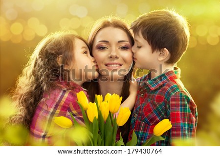 Portrait of children kissing her mother with flowers. Spring, March 8, International Womens, Mothers day, family holiday