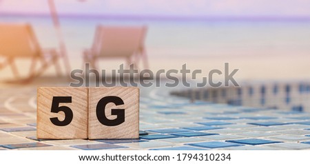 5G letters on wooden blocks standing on swimming pool borders mosaic near the beach. Big data fast internet concept