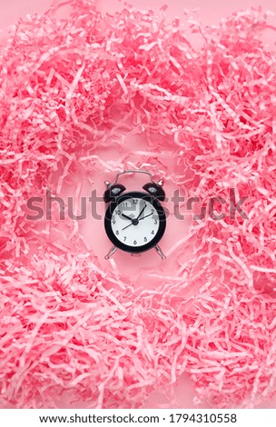 alarm clock on a pink background in paper tinsel. minimal creative style. Holiday time, deadline, time management concept.