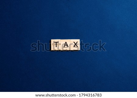 Wooden blocks with the word " tax " on a classic blue background. concept of business and Finance.