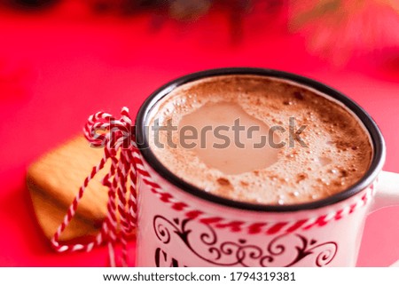 Hot cocoa in a mug on the holiday table with Christmas garland and spruce branches