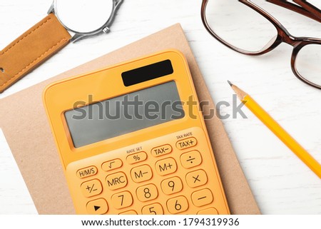 Calculator, notebook, watch and glasses on white wooden table, flat lay. Tax accounting