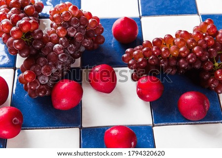 Plums and grapes on tiles