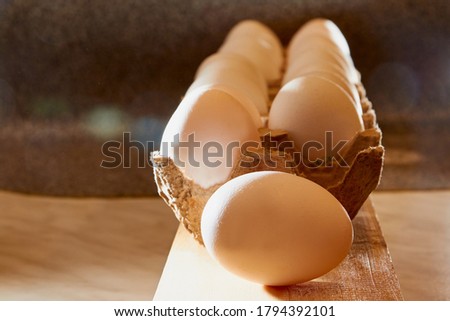 White chicken eggs in cardboard on wooden surface with interesting light. The concept of taking pictures of food. Fresh eggs from the farm. Organic egg production. Chicken egg industry. Eggs for sale