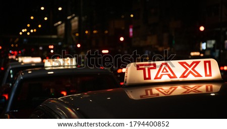 Taxi cab roof illuminated sign with blurry background at night (translation: TAXI)
