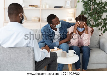 Caring Husband Comforting Black Wife Having Mental Health Problems After Coronavirus, Sitting At Therapist Office Together Royalty-Free Stock Photo #1794402982