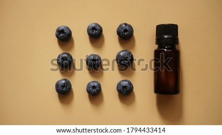 A bottle of blueberry seed essential oil and fresh blueberries on gold background