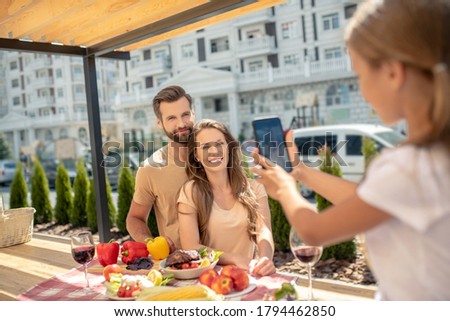 Happy family. Fair-haired girl making picture of her smiling parents