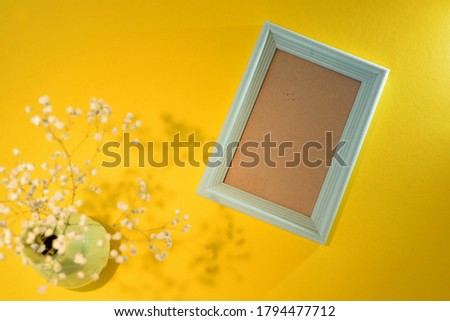 blue empty photo frame on yellow background with vase and flower mockup  Space for text, Copyspace, Space for photo