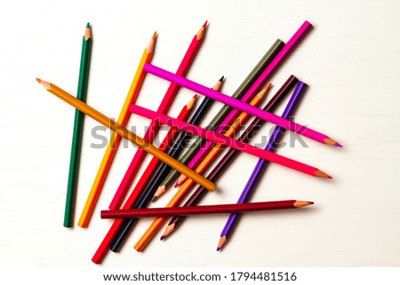 many colored sharpened pencils lie on a white wooden table