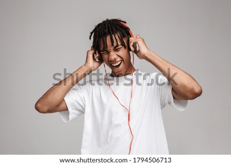 Black african young happy man having fun listening to music isolated over gray background