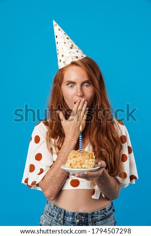 Young shocked woman with a cake over isolated blue background, surprise and shocked facial expression
