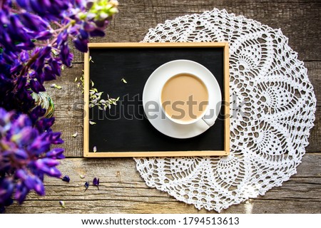 Top view of lupines, chalk board and white cup with cocoa on an old wooden background.