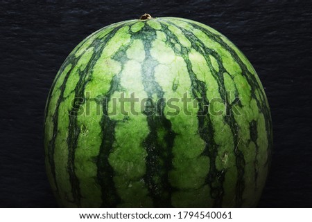 Photograph of a watermelon on slate background.
