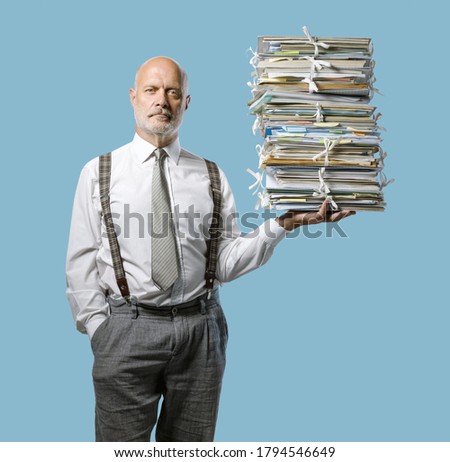 Confident businessman holding a pile of paperwork effortlessly with one hand, easy business administraton concept Royalty-Free Stock Photo #1794546649