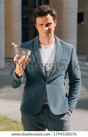 Frustrated male European holds a food cart mini version. the concept of online shopping store