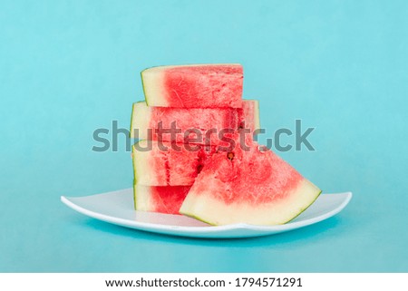 Water melon slices on a plate on blue background. Juicy fresh tasty summer dessert. Stock photo