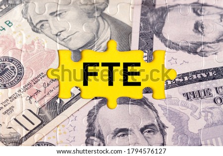 Business concept. Puzzle with the image of dollars in the center of the inscription -FTE