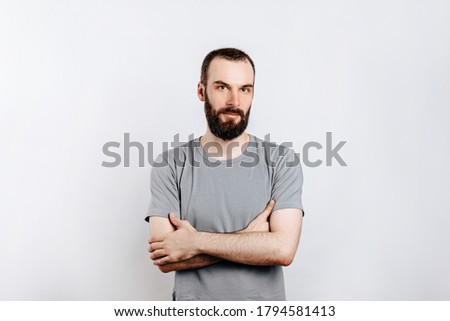 Portrait of a handsome brutal brunette serious man on a white background with crossed arms. The person will soon become the owner of a startup business.