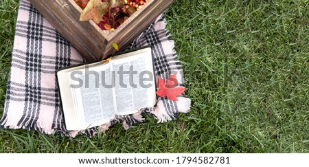 Bible in autumn with blanket , basket and some leaf.