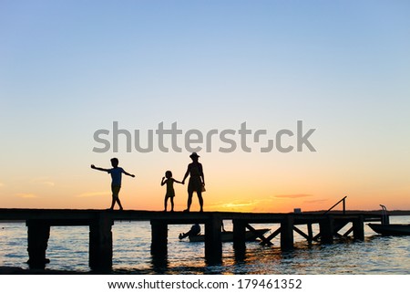 Family silhouettes on a bridge at sunset