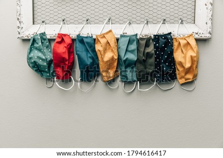 A row and variety of colorful protective face masks hanging on a home bulletin type clipboard for going back to work or back to school  for easy access with copy space Royalty-Free Stock Photo #1794616417