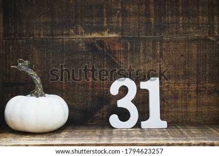 Halloween background concept with number 31 and white pumpkin on wooden background