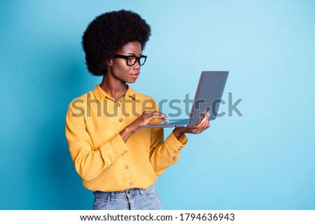 Photo of black skin big volume hairstyle serious calm woman hold laptop working managing remote online graphic design project wear specs jeans yellow shirt isolated blue color background