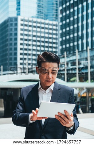 Business man using tablet in city outdoor with office buildings in the background stock photo